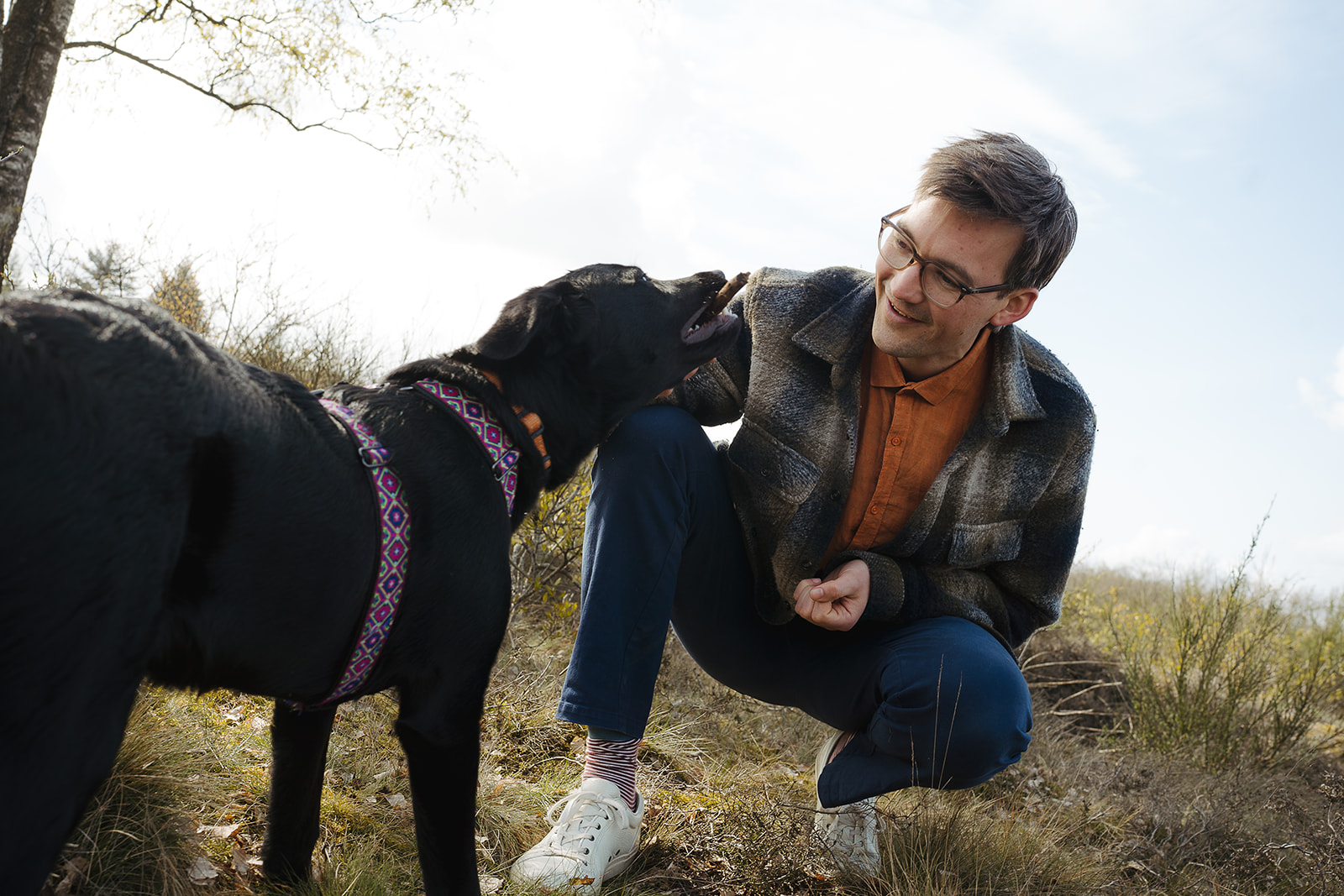Stanley zit buiten naast een hond en kijkt hem vriendelijk aan.